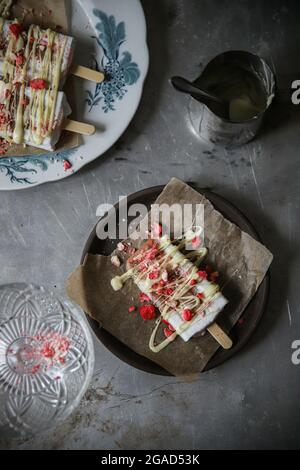Blick von oben auf Vanilleeis auf einem Stock mit weißer Schokolade und gefrorenen Himbeeren Stockfoto