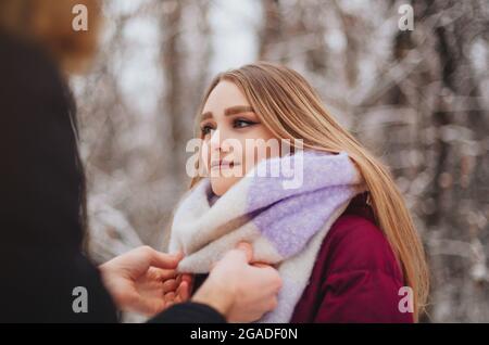 Beschnittenes Foto von schönen jungen Teenager-Paar verbringen Zeit zusammen draußen im kalten Winter, Kerl Richten gestrickten Mädchen Schal, um sie warm zu halten Stockfoto