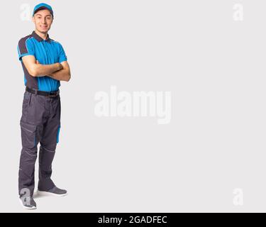 Das Foto eines in graublauer Uniform gelieferten Mannes in voller Länge faltete seine Arme auf der Brust und schaute auf die Kamera. Stockfoto