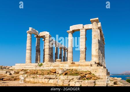 Der antike griechische Tempel von Poseidon am Kap Sounion, dorische Säulen und Ruinen auf dem Hügel mit kristallblauem Himmel Hintergrund. Stockfoto