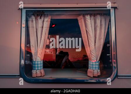 Blick in einen niedlichen Vintage-Bus durch ein kleines Fenster mit Vorhängen Stockfoto