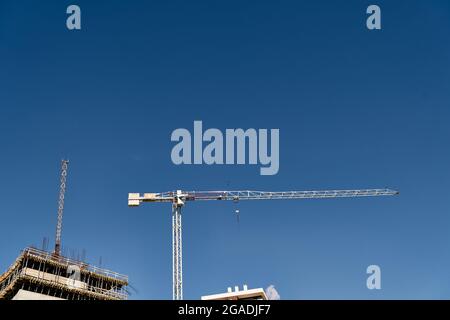 Der hohe Baukran ragt über eine Baustelle vor blauem Himmel Stockfoto