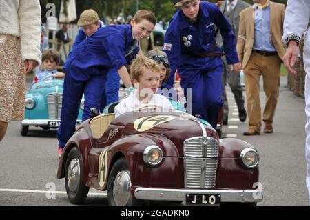 Settrington Cup Kinderrennfahrer in Austin J40 Pedalwagen beim Goodwood Revival. Kleine Kinder Fahrer und Team Mechaniker Stockfoto