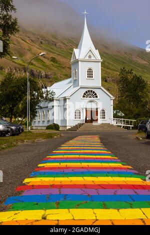 Die Regenbogenstraße Nordurgata zur hübschen blauen Kirche in seydisfjordur wurde 2016 gemalt Stockfoto
