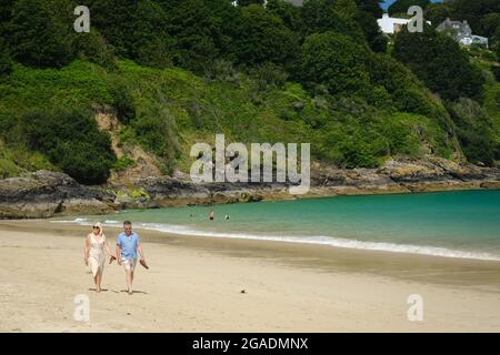 Ein Paar mittleren Alters, das am Strand von Carbis Bay in Cornwall, Großbritannien, entlang läuft. Stockfoto