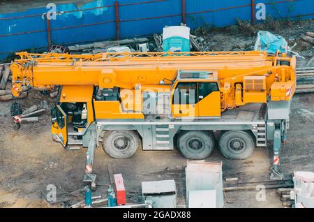 Viele LKW und Krane auf dem Gelände bestehen aus Heben, Riemenscheibe, Schlinge, Derrick sind bereit für den Bau Stockfoto