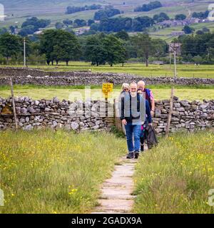 Familie, die über eine Wiese auf einem alten Steinpfad auf den Hawes zum Hardraw Force Walk, Yorkshire Dales National Park, geht. Stockfoto