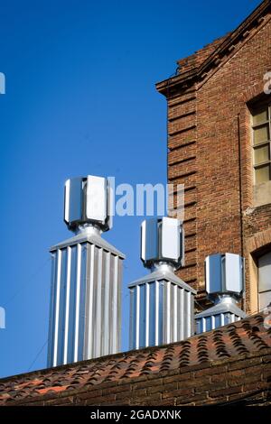 Neue Stahlschornsteine auf einem alten industriellen Umfeld, blauer Himmel. Stockfoto