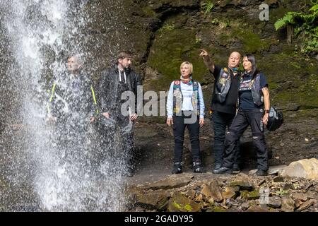 Eine Gruppe von Motorradfahrern in Lederkleidung in Hardraw Force, Wensleydale, die in einer Gruppe hinter dem Wasserfall, dem Yorkshire Dales National Park, stehen Stockfoto