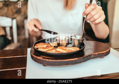 Frau isst im Straßencafe hausgemachte vegane Kartoffelpfannkuchen auf einem Teller. Traditionelles, köstliches Essen Stockfoto