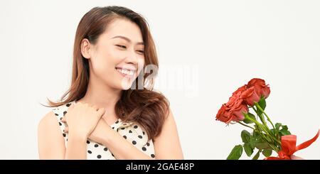 Charmantes zartes Mädchen hält rote Rosen in den Händen und schaut nachdenklich zur Seite. Foto auf weißem Hintergrund. Stockfoto