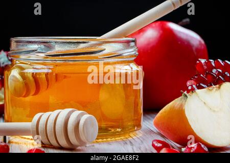 Traditioneller jüdischer religiöser Feiertag Rosh Hashanah. Äpfel, Granatäpfel und Honig auf dunklem Holzhintergrund. Stockfoto