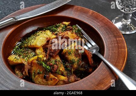 Geröstete Kartoffeln mit Fleisch, Zwiebeln und Dill in Tonteller Stockfoto