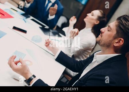 Das Team von Geschäftsleuten meditiert und hält sich nach dem Büromeeting die Hände. Business People Group Konferenz Diskussion Meditationskonzept Stockfoto