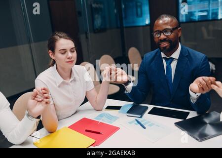 Das Team von Geschäftsleuten meditiert und hält sich nach dem Büromeeting die Hände. Business People Group Konferenz Diskussion Meditationskonzept Stockfoto