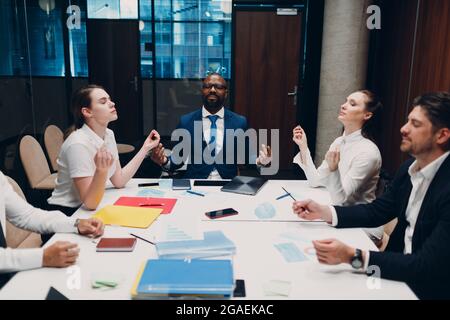 Das Team von Geschäftsleuten meditiert und hält sich nach dem Büromeeting die Hände. Business People Group Konferenz Diskussion Meditationskonzept Stockfoto