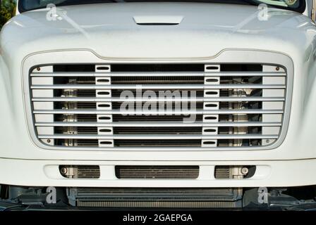 Frontgrill eines generischen weißen Lkw, abstrakte Nahaufnahme auf Augenhöhe mit sichtbarer Haube. Stockfoto