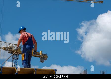 Nicht erkennbarer Bauarbeiter mit Schutzhelm, der an einem Neubau auf der Baustelle arbeitet Stockfoto