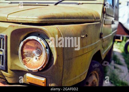 Fragment der Vorderseite eines alten rostigen Autos mit einem defekten Scheinwerfer Stockfoto