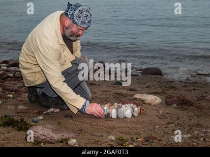 Der Landkünstler James Brunt kreiert am Strand, Dunbar, East Lothian, Schottland, Großbritannien, eine Stein- oder Felsskulptur Stockfoto