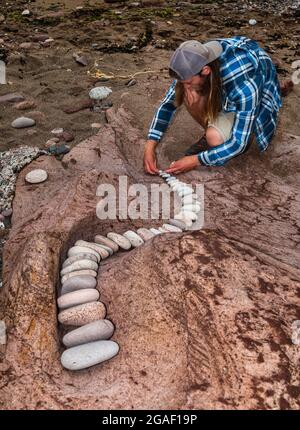 Jon Foreman, Landkünstler, kreiert eine spiralförmige Rkok- oder Steinskulptur am Strand, Dunbar, East Lothian, Schottland, Großbritannien Stockfoto