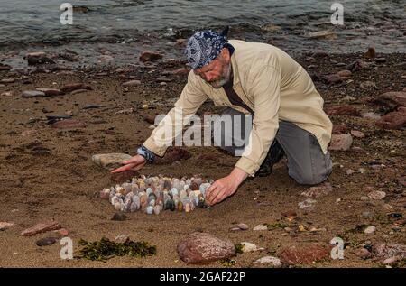 Der Landkünstler James Brunt kreiert am Strand, Dunbar, East Lothian, Schottland, Großbritannien, eine Stein- oder Felsskulptur Stockfoto