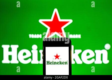 In dieser Abbildung ist ein Heineken-Logo auf einem Smartphone mit einem Heineken-Logo im Hintergrund zu sehen. Stockfoto