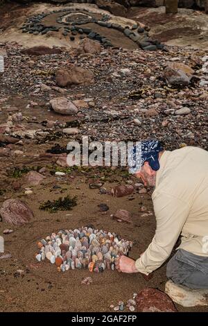 Der Landkünstler James Brunt kreiert am Strand, Dunbar, East Lothian, Schottland, Großbritannien, eine Stein- oder Felsskulptur Stockfoto