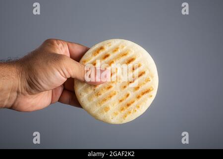 Der Mensch hält Arepa, eine Art von Mahl, die traditionell in der Küche Kolumbiens und Venezuelas zubereitet wird Stockfoto