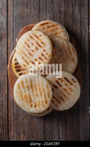 Arepa ist eine Art Mahlzeit aus gemahlenem Maisteig, Maismehl, Draufsicht, Holzhintergrund Stockfoto