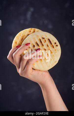 Woman Holds arepa ist eine Art Mahl aus Maismehl, traditionell in der Küche von Kolumbien und Venezuela, dunkler Rücken Stockfoto