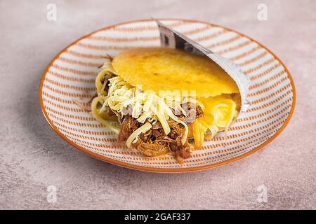 Gefüllte Arepa auf einem Teller aus Maismehl, traditionelle Küche von Kolumbien und Venezuela zubereitet Stockfoto