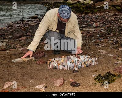 Der Landkünstler James Brunt kreiert am Strand, Dunbar, East Lothian, Schottland, Großbritannien, eine Stein- oder Felsskulptur Stockfoto