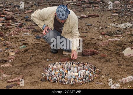 Der Landkünstler James Brunt kreiert am Strand, Dunbar, East Lothian, Schottland, Großbritannien, eine Stein- oder Felsskulptur Stockfoto