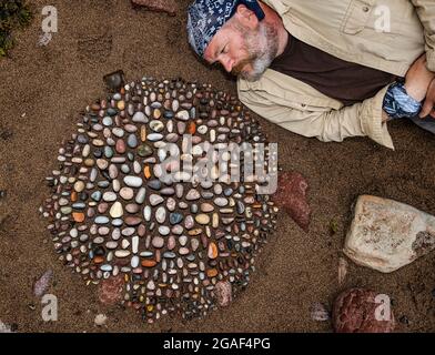 Der Landkünstler James Brunt kreiert am Strand, Dunbar, East Lothian, Schottland, Großbritannien, eine Stein- oder Felsskulptur Stockfoto