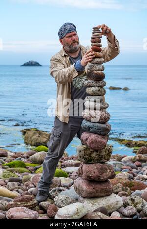 James Brunt, Landkünstler, stapelt Steine in einem Turm bei der European Stone Stacking Championship on the Beach, Dunbar, East Lothian, Schottland, Großbritannien Stockfoto