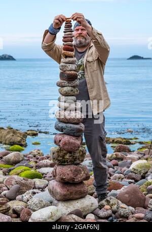 James Brunt, Landkünstler, stapelt Steine in einem Turm bei der European Stone Stacking Championship on the Beach, Dunbar, East Lothian, Schottland, Großbritannien Stockfoto