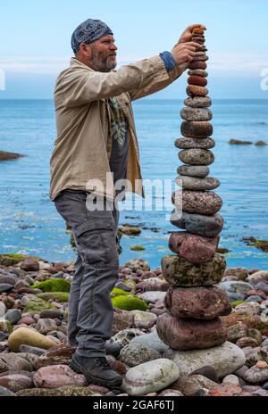 James Brunt, Landkünstler, stapelt Steine in einem Turm bei der European Stone Stacking Championship on the Beach, Dunbar, East Lothian, Schottland, Großbritannien Stockfoto