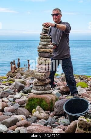 Jonathon Kitching stapelt Steine in einem Turm bei der European Stone Stacking Championship am Strand, Dunbar, East Lothian, Schottland, Großbritannien Stockfoto