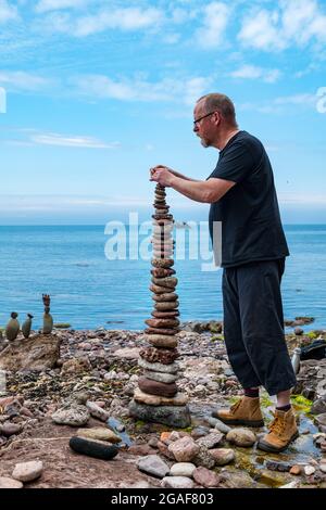 Neil Andrews stapelt Steine in einem Turm bei der European Stone Stacking Championship on the Beach, Dunbar, East Lothian, Schottland, Großbritannien Stockfoto