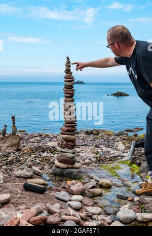 Neil Andrews stapelt Steine in einem Turm bei der European Stone Stacking Championship on the Beach, Dunbar, East Lothian, Schottland, Großbritannien Stockfoto