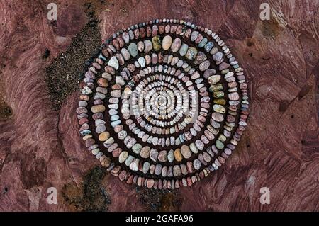 Draufsicht auf ein spiralförmiges Muster aus Kieselsteinen oder Steinen an einem felsigen Strand, Dunbar, East Lothian, Schottland, Großbritannien Stockfoto