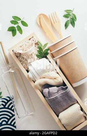 Umweltfreundliches Utensil und verschiedene Einkaufstaschen in Holzkiste auf weißem Hintergrund. Kein Abfall, plastikfreies Produktset. Stockfoto