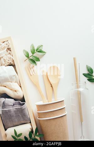 Umweltfreundliches Geschirr, Glas-Wasserflasche, Holzkiste mit Baumwolltaschen auf weißem Hintergrund. Zero Waste, plastikfreies Konzept Stockfoto