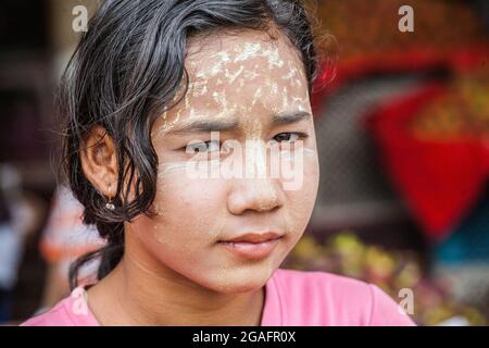 Hübsches junges burmesisches Mädchen mit Thanaka-Gesichtspuder auf Stirn und Nase, die für Fotos posiert, Yangon, Myanmar Stockfoto