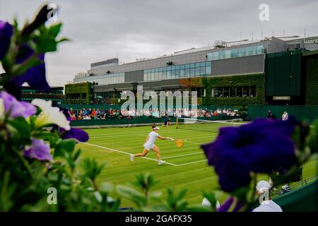 Tamara Zidansek aus Solvakia im Kampf zwischen Blumen während ihres Spiels gegen Karolina Pliskova aus Tschechien in Wimbledon Stockfoto