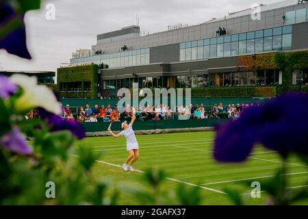 Tamara Zidansek aus Solvakia im Kampf zwischen Blumen während ihres Spiels gegen Karolina Pliskova aus Tschechien in Wimbledon Stockfoto