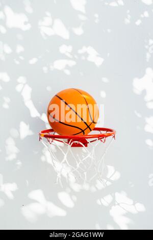 Basketballkorb an einer weißen Wand. Der Ball, der kurz vor dem Ring steht. Stockfoto