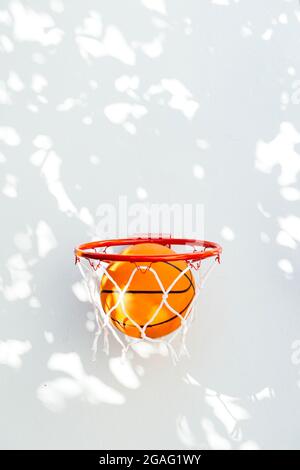 Basketballring an einer weißen Wand. Der Ball fällt durch den Reifen. Stockfoto