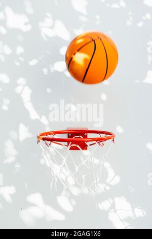 Basketballkorb an einer weißen Wand. Der Ball, der kurz vor dem Ring steht. Stockfoto